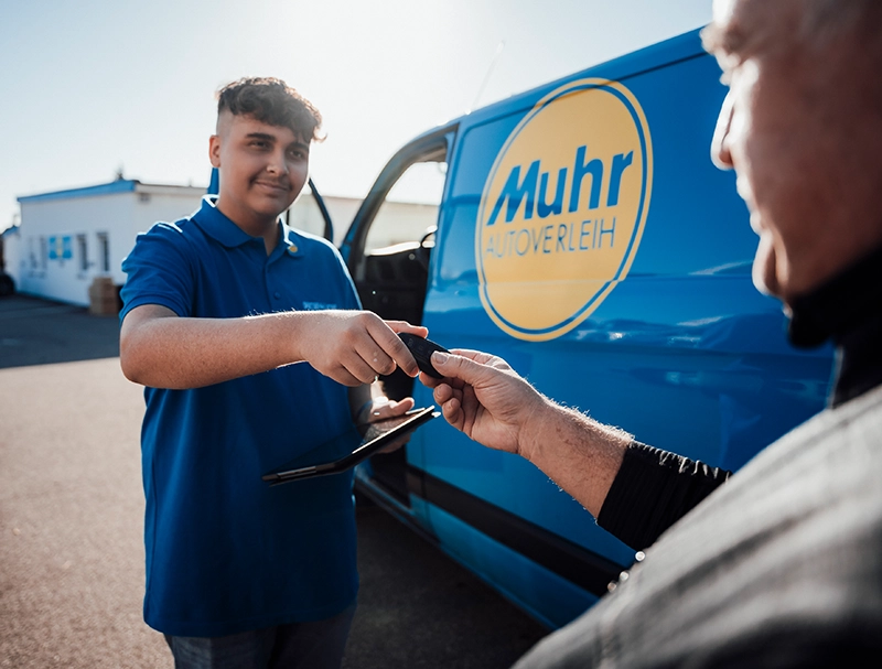 Transporter zu leihen - Muhrmitarbeiter bei der Schlüsselübergabe eines Umzugtransporters an einen Kunden