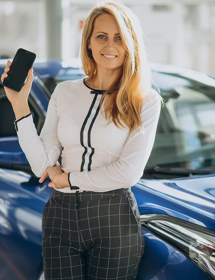 Flexible Mietmodelle Muhr Autoverleih - Geschäftsfrau mit Handy in der Hand lehnt an einem Firmenwagen