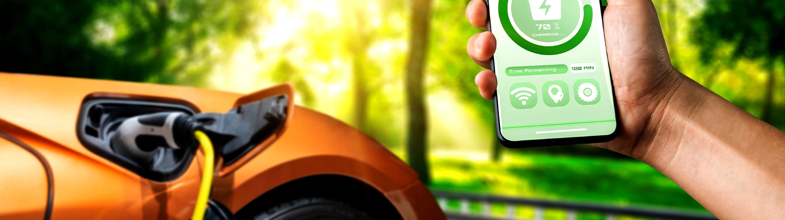 E-Auto Reise planen - E-Auto beim Laden und im Vordergrund wird ein Handy mit App für das E-Auto gezeigt