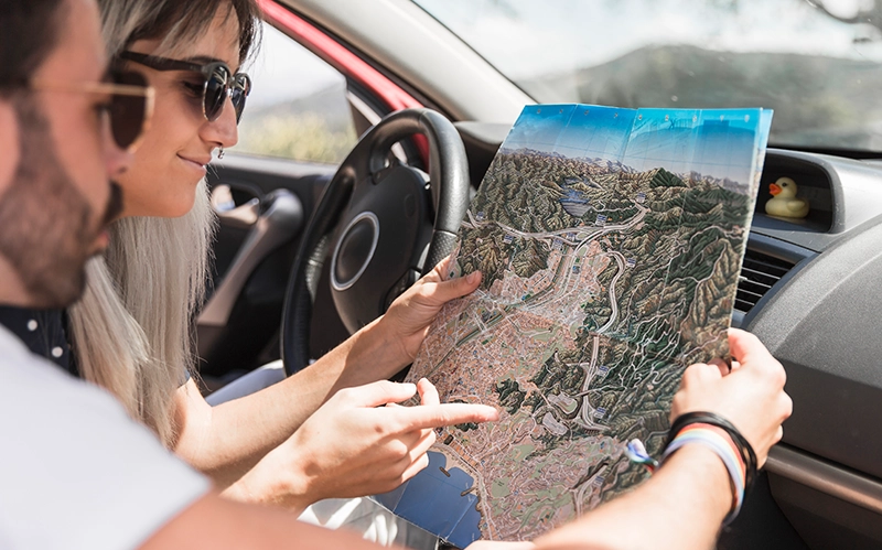 Panoramarouten Deutschlands - Frau und Mann sitzen im Auto und schauen zusammen auf eine Landkarte